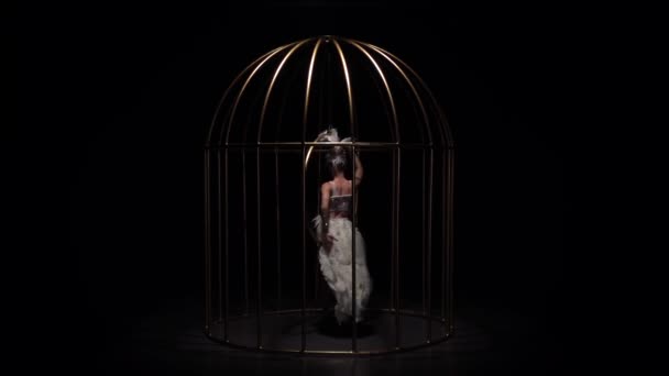 Graceful girl gymnast riding a hoop in a cage on dark stage. Black background. Slow motion — Stock Video