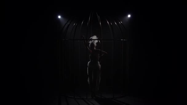 Acrobaties sur un cercle rotatif dans une cage dans une pièce sombre. Fond noir. Silhouette. Mouvement lent — Video