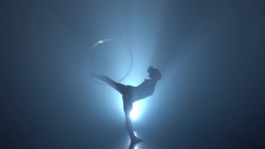 Jimnastikçi bir metal çember kolunu ve bacağını daha sonra katlanmış. Duman arka plan