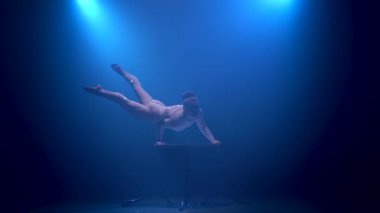 Acrobat kız sahnede akrobatik stunts ellerinin üzerinde duran yok. Mavi renkli duman. Siluet
