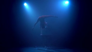 Jimnastikçi stüdyo tabloda hileler gerçekleştirir. Mavi renkli duman. Siluet