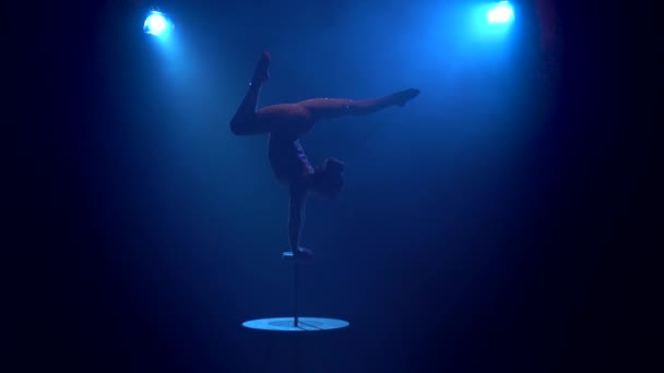 Gymnastka dívka na stole ukazuje akrobatické kousky. Kouř modré pozadí. Silueta — Stock video