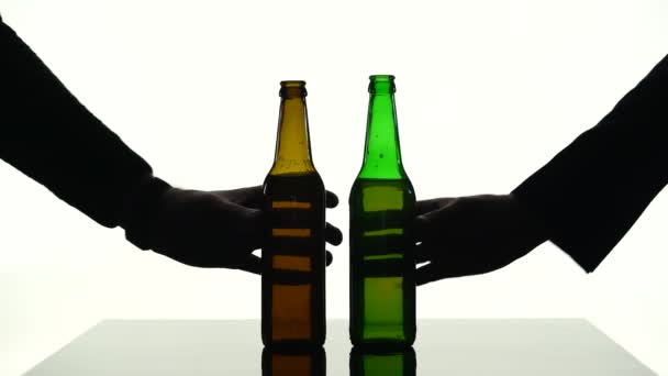 Due bottiglie di birra messe sul tavolo allo stesso tempo. Silhouette sfondo bianco — Video Stock
