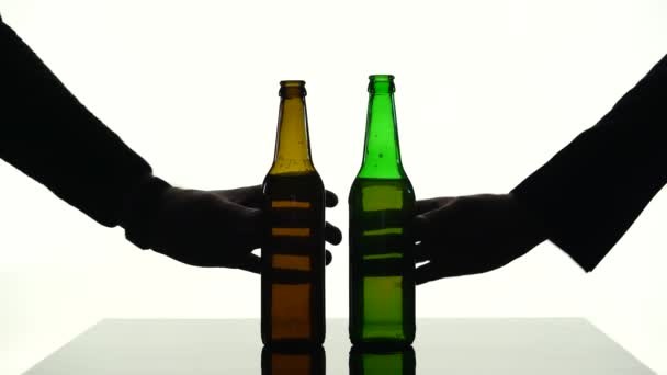 Zwei Bierflaschen gleichzeitig auf den Tisch gestellt. Silhouette weißer Hintergrund — Stockvideo