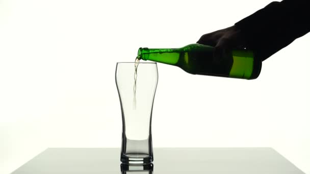 Öl hälla i ett glas som ligger på bordet. Silhouette vit bakgrund — Stockvideo