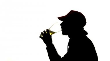 Adam bir bardak bira içiyor. Yan görünümü. Beyaz arka plan siluet