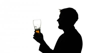 Adam bir bardak bira içiyor. Yan görünümü. Beyaz arka plan siluet