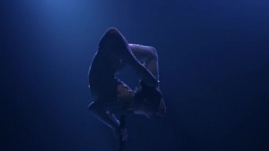 Jimnastikçi köprüde duruyor. Mavi renkli duman. Ağır çekim. Siluet