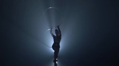 Jimnastikçi havadaki basketbol elleri katlanmış. Ağır çekim. Duman arka plan. Siluet