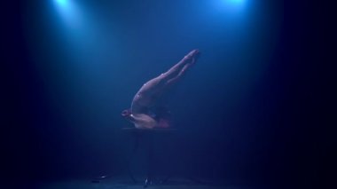 Jimnastikçi stüdyo tabloda hileler gerçekleştirir. Mavi renkli duman. Ağır çekim