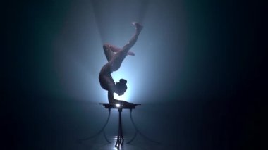 Acrobat kız hileler yürütür. Duman arka plan. Ağır çekim. Siluet