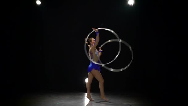 Akrobat mit Reifen in der Hand führt verschiedene Kunststücke vor. Zeitlupe. schwarzer Hintergrund. Seitenansicht — Stockvideo