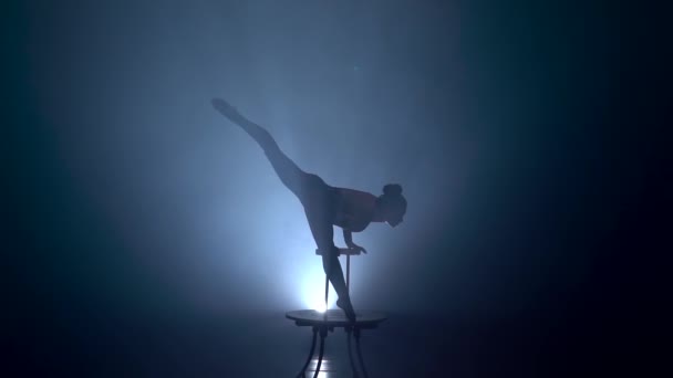 Acrobat girl holds her body in the air with one hand. Smoke background. Slow motion. Silhouette — Stock Video