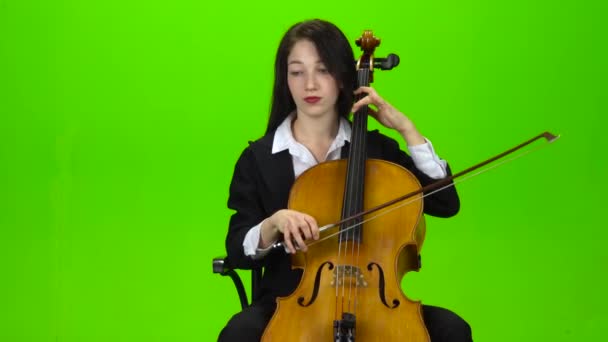 La chica se sienta y toca el violonchelo. Pantalla verde — Vídeo de stock