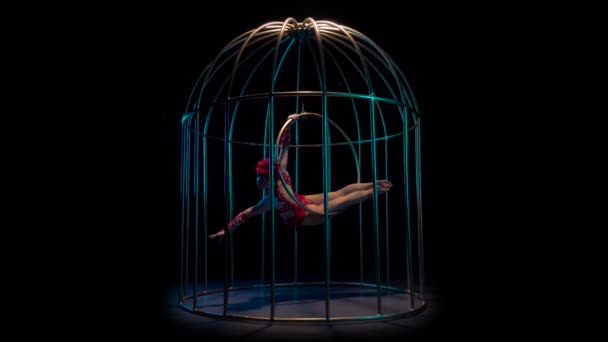 Aerial gymnastics rotates on a hoop in a cage. Black background. Slow motion — Stock Video