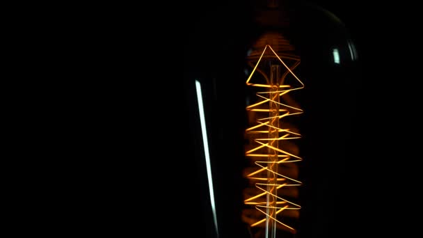Edison lamp slowly lights up, sacros, black background — Stock Video
