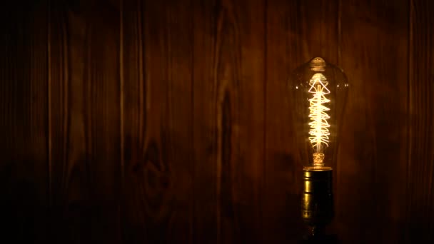 Light bulb illuminates on wooden background — Stock Video