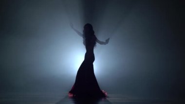 Egzotik dansöz kadın onu kalça sallayarak. Duman arka plan. Sihouette
