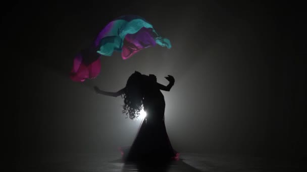 Chica con un velo en sus manos bailando danza del vientre. Sihouette. Fondo de humo negro — Vídeos de Stock