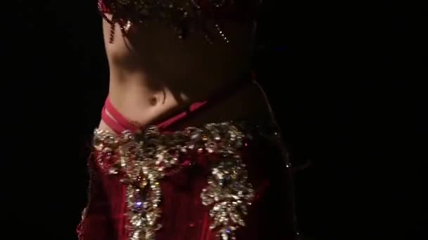 Torso of a belly dancer who is starting shaking her hips. Black background. Slow motion. Close up — Stock Video