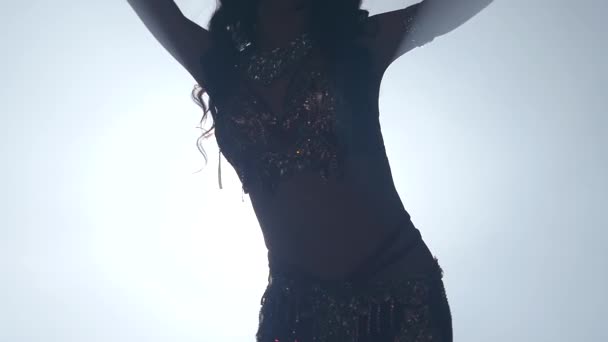 Torso of a belly dancer who is starting shaking her hips. Smoke background. Slow motion. Close up. Sihouette — Stock Video