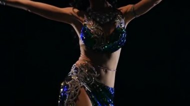 Karanlıkta kız gövdesinde oryantal dansçı. Siyah arka plan. Yavaş hareket. Yakın çekim