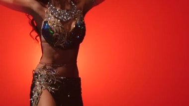 Kız karanlık bir stüdyo oryantal dans gerçekleştirir. Kırmızı duman arka planı. Yavaş hareket. Yakın çekim