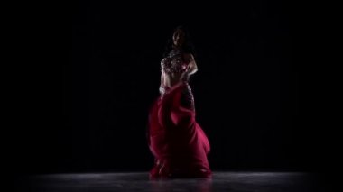 Kalça sallayarak başlayan kadın oryantal dansçı. Siyah arka plan. Yavaş hareket