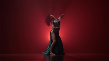 Tal, uzun saçlı egzotik dansçı kız dans gidin. Kırmızı duman arka planı. Yavaş hareket