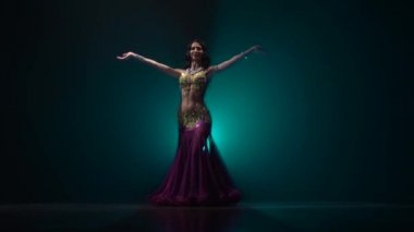 Kız oryantal kostüm karanlık bir stüdyo oryantal dans gerçekleştirir. Duman geçmişi. Yavaş hareket