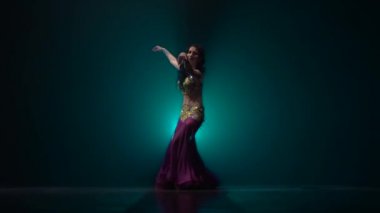 Karanlık sahnede duman arka planda geleneksel oryantal dansçı kız dans. Yavaş hareket