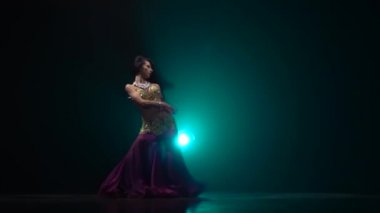 Karanlık sahnede duman arka planda geleneksel oryantal dansçı kız dans. Yavaş hareket