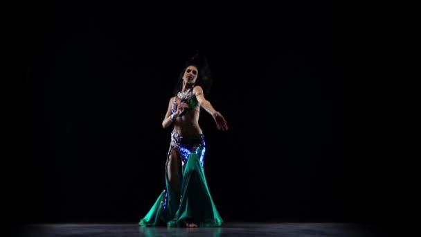 Flickan uppträder i en mörk Studio magdans. Svart bakgrund. Slow motion — Stockvideo