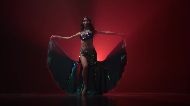 Dlouhovlasá exotická břišní tanečnice tančí na tanci. Červené kouřové pozadí. Zpomaleně — Stock video