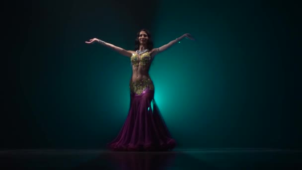 Дівчина виступає в темному студійному танці живота в східному костюмі. Дим фону. Повільний рух — стокове відео