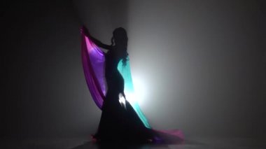 Göbek dansçı kız eller şifon bez ile bükümler. Sihouette, hayır. Siyah duman arka plan. Yavaş hareket
