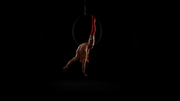 Danseres vrouwelijke balancer in beige leotard terug liggend hangen op de lucht hoepel op zwarte achtergrond — Stockvideo
