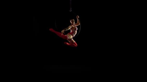 Chica gimnasta del aire dando vueltas en el aro aéreo. Fondo negro — Vídeos de Stock