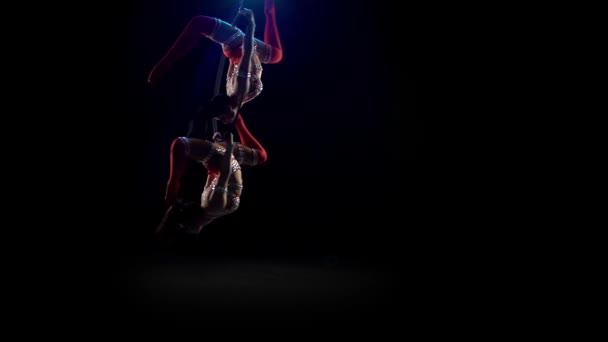 Dva akrobaté dělají gymnastický prvek na leteckém triku. Černé pozadí kouře — Stock video
