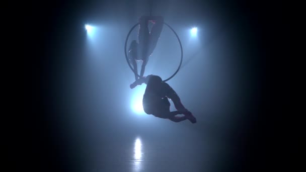 Gymnasts voert een truc in de lucht hoepel uit. Zwarte rook achtergrond. Silhouet — Stockvideo