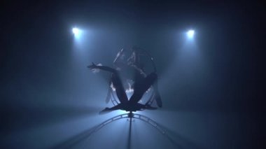 Sahne profesyonel jimnasir üzerinde spin. Siyah duman arka plan. Siluet