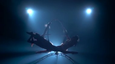 Kızlar hava akrobasi için bir çember içinde dolaşan. Siyah duman arka plan. Siluet. Yavaş hareket