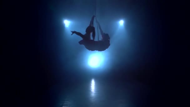 Girls performs a trick in the aerial hoop. Black smoke background. Silhouette. Slow motion — Stock Video