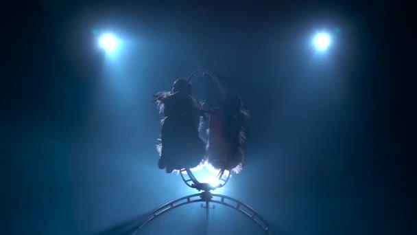 Girls air acrobats rotate in the air on a metal hoop. Black smoke background. Silhouette. Slow motion — Stock Footage Girls air acrobats rotate in the air on a metal hoop. Black smoke background. Silhouette. Slow motion Stock Footage