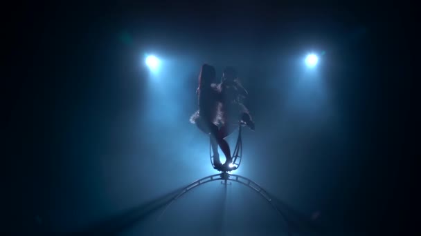 空気アクロバットの女の子が空気中の金属のフープを優雅に回転させます。黒の煙の背景。シルエット。スローモーション — ストック動画