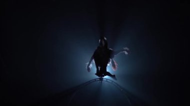 Profesyonel jimnasmeler spin ve çeşitli stunts gerçekleştirin. Siyah duman arka plan. Siluet. Yavaş hareket