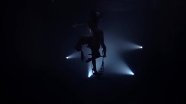 İki esnek Jimnastikteki hava çemberinde hüner gerçekleştirir. Siyah duman arka plan. Yavaş hareket. Siluet