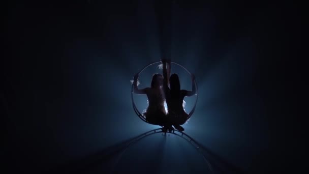 女の子の空気のアクロバットは、金属のフープに空中で回転します。黒の煙の背景。シルエット。スローモーション — ストック動画