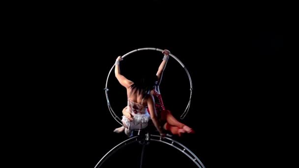 Gymnasts performs a trick on the aerial hoop metal construction. Black background. Slow motion — Stock Video