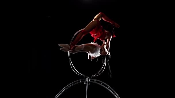 Trick on the aerial hoop metal construction two gymnasts performs. Black background. Slow motion — Stock Video